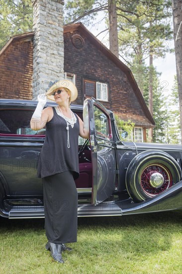 Attractive young woman in twenties outfit near antique automobile