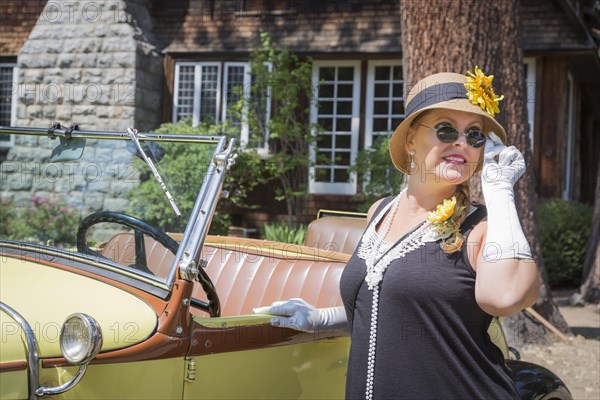 Attractive young woman in twenties outfit near antique automobile