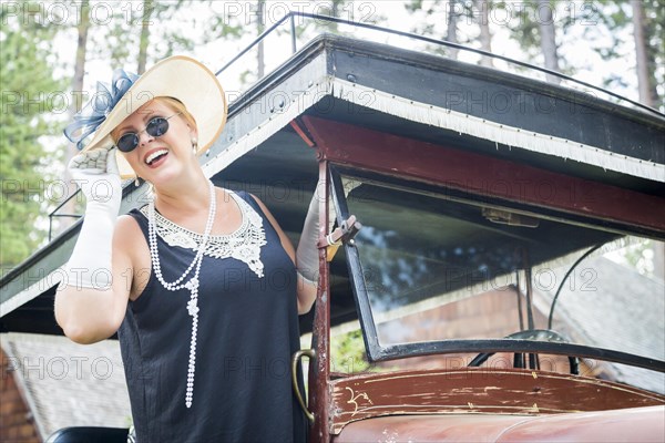 Attractive young woman in twenties outfit near antique automobile