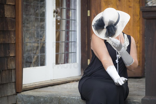 Attractive young woman in twenties outfit on porch of an antique house