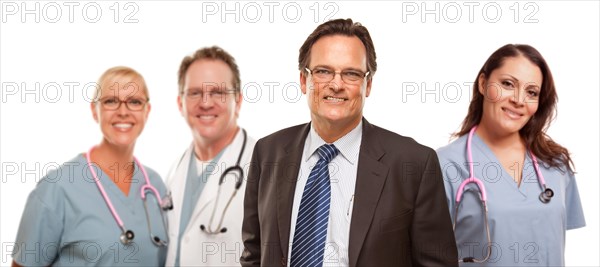 Smiling businessman in suite and tie while male and female doctors and nurses stand behind isolated on a white background