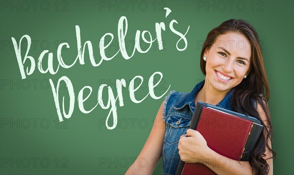 Bachelors degree written on chalk board behind mixed-race young girl student holding books