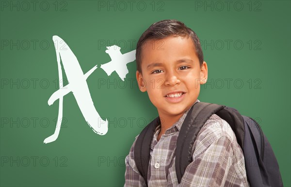 Cute hispanic boy in front of A+ written on chalk board