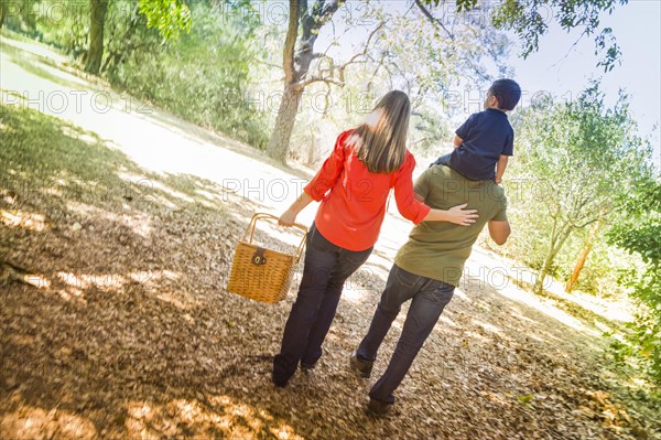 Happy mixed-race family with picnic basket enjoy a walk in the park