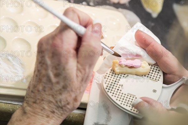 Female dental technician applying porcelain to A 3D printed implant mold in the lab