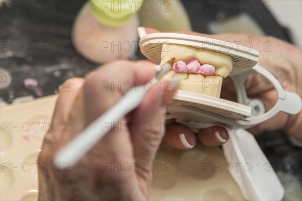 Female dental technician applying porcelain to A 3D printed implant mold in the lab