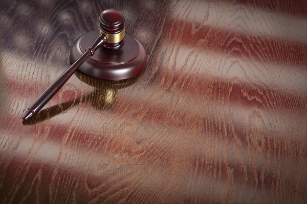 Wooden gavel resting on american flag reflecting table