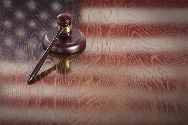 Wooden gavel resting on american flag reflecting table