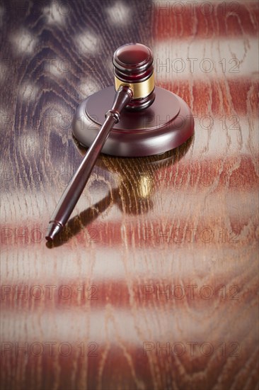 Wooden gavel resting on american flag reflecting table