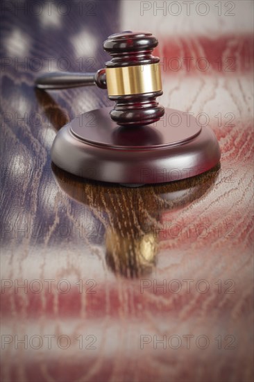 Wooden gavel resting on american flag reflecting table