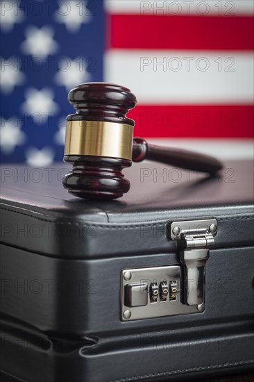 Leather briefcase and gavel resting on table with american flag behind