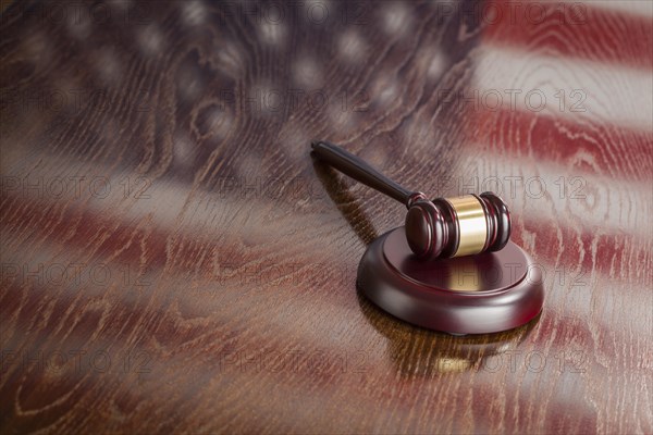 Wooden gavel resting on american flag reflecting table