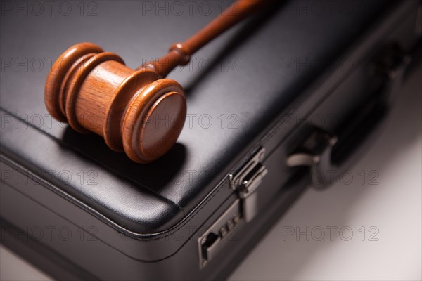 Gavel and black briefcase on gradated background with selective focus