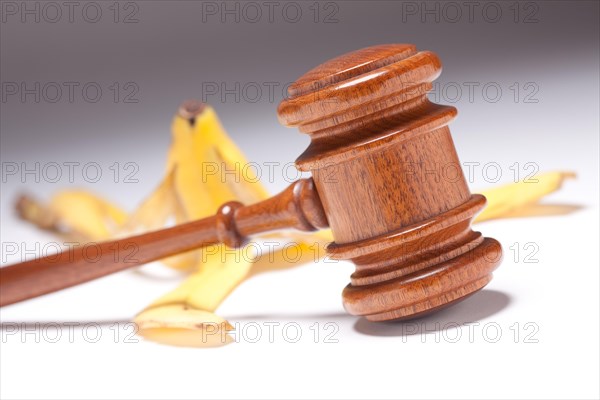 Gavel and banana peel on gradated background with selective focus