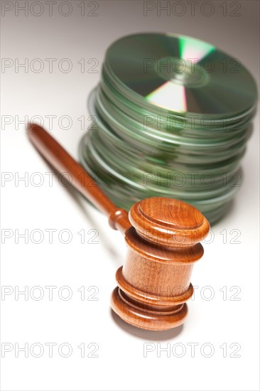 Stack of CD rom or DVD discs and gavel on a gradated background