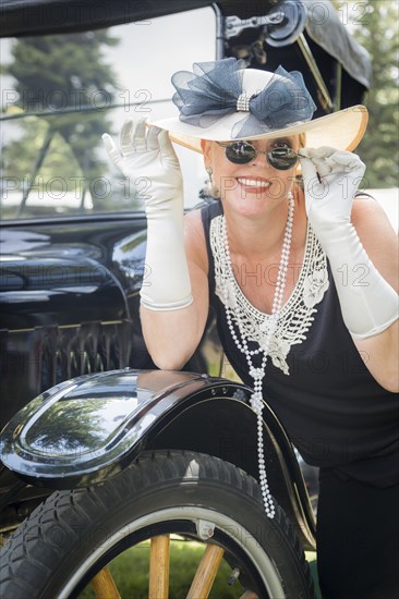 Attractive woman in twenties outfit near antique automobile