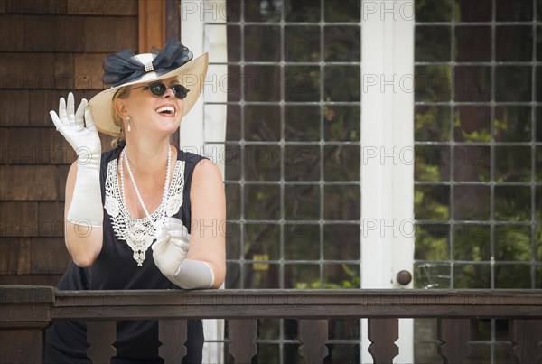 Attractive young woman in twenties outfit on porch of an antique house
