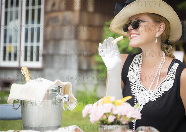 Attractive twenties dressed woman eating and drinking champagne at outdoor party