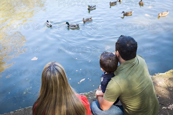 mixed-race mother and father with son at the park duck pond