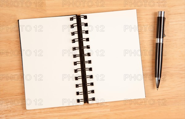 Blank spiral note pad and pen on wood background