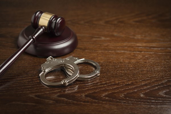 Gavel and pair of handcuffs on wooden table