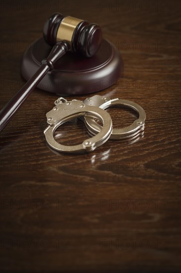 Gavel and pair of handcuffs on wooden table