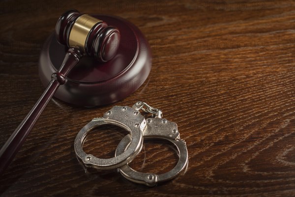 Gavel and pair of handcuffs on wooden table