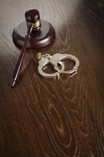 Gavel and pair of handcuffs on wooden table