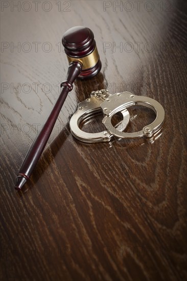 Gavel and pair of handcuffs on wooden table