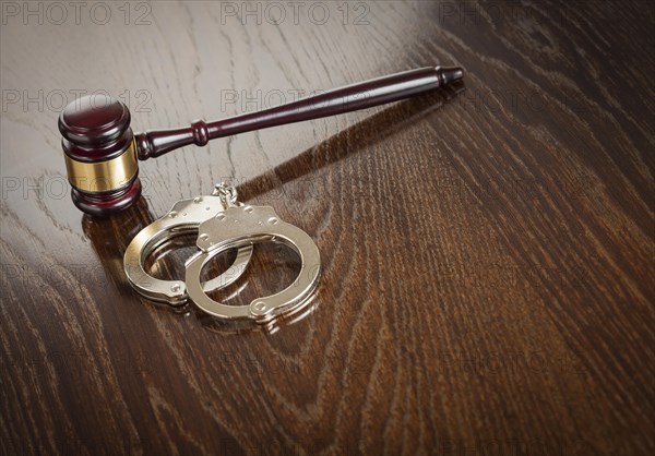 Gavel and pair of handcuffs on wooden table