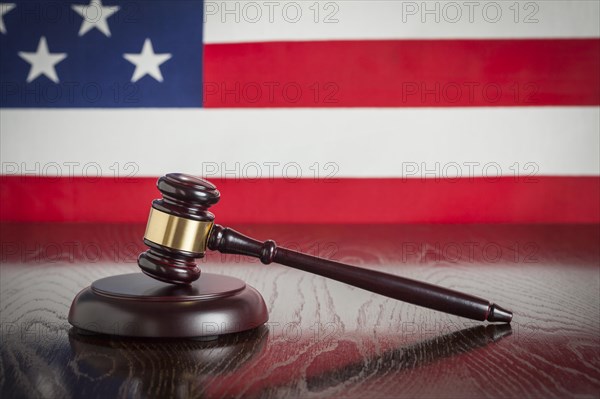 Wooden gavel resting on american flag reflecting table