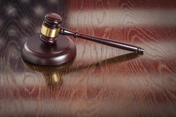 Wooden gavel resting on american flag reflecting table