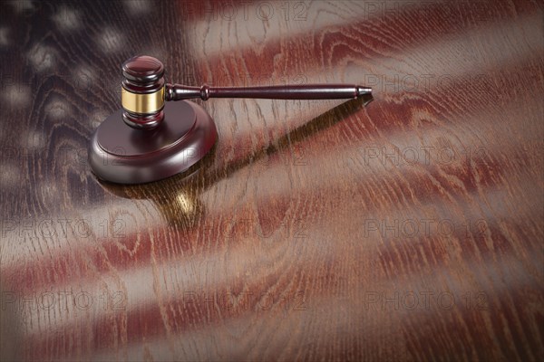 Wooden gavel resting on american flag reflecting table