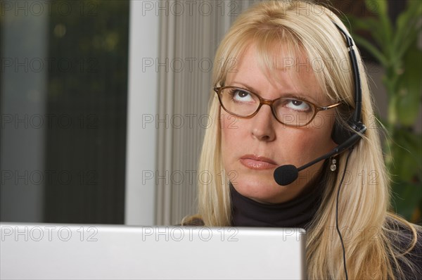 Attractive businesswoman shows signs of boredom while on her phone headset