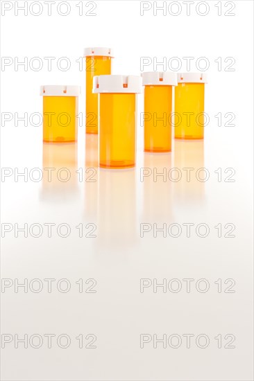 Several different sized empty medicine bottles on reflective surface