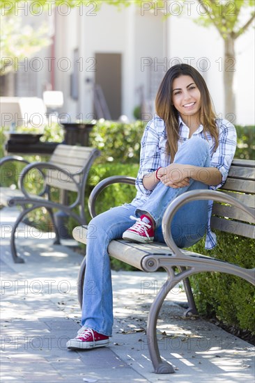 Happy mixed-race female student portrait on school campus bench