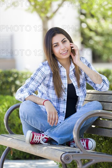 Happy mixed-race female student portrait on school campus bench