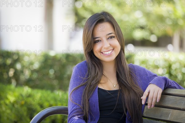 Happy mixed-race female student portrait on school campus bench