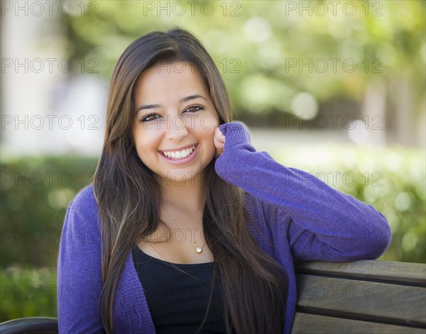 Happy mixed-race female student portrait on school campus bench