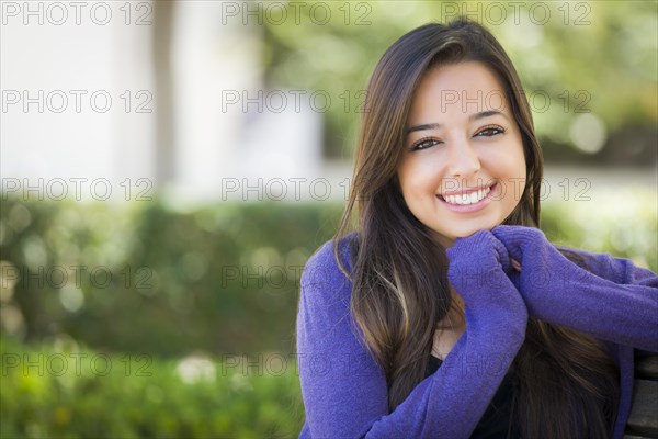 Happy mixed-race female student portrait on school campus bench