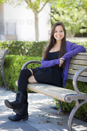 Happy mixed-race female student portrait on school campus bench