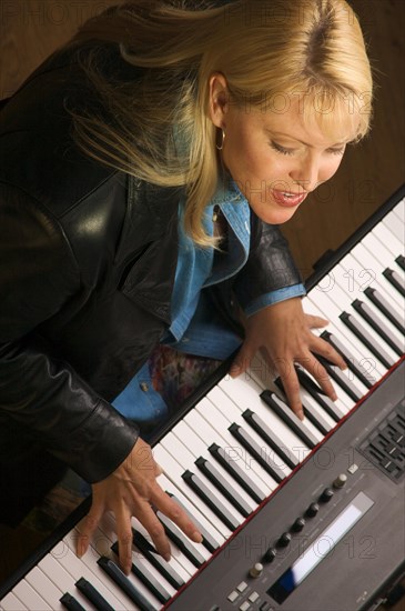 Female musician sings while playing digital piano