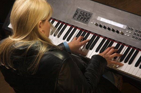 Female musician sings while playing digital piano