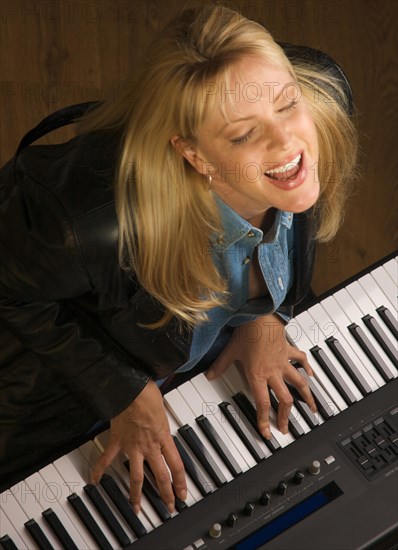 Female musician sings while playing digital piano