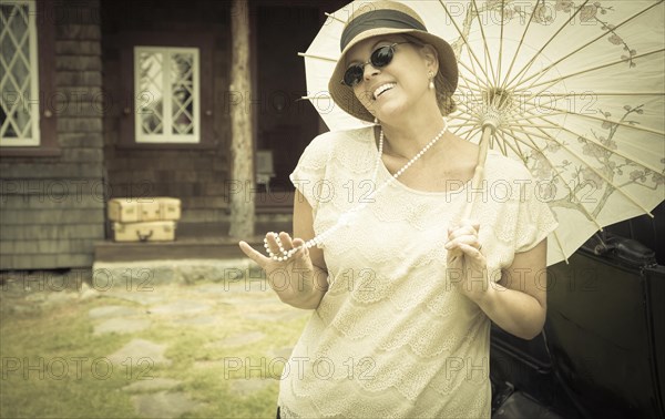 Beautiful 1920s dressed girl with parasol near vintage car