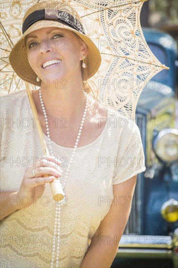 Beautiful 1920s dressed girl with parasol near vintage car portrait