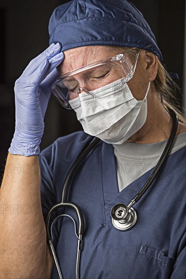 Grimacing female doctor or nurse wearing protective facial wear and surgical gloves