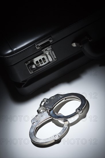 Pair of handcuffs and briefcase under spot light abstract