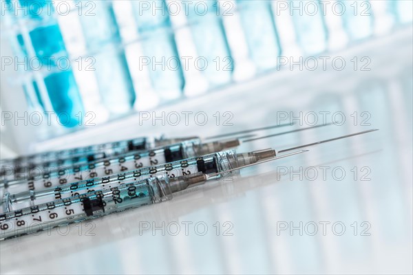 Abstract of scientific needle syringes and test tubes containing blue chemical in rack