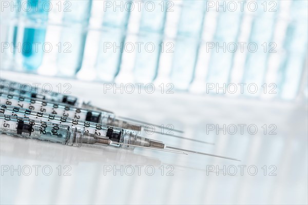 Abstract of scientific needle syringes and test tubes containing blue chemical in rack